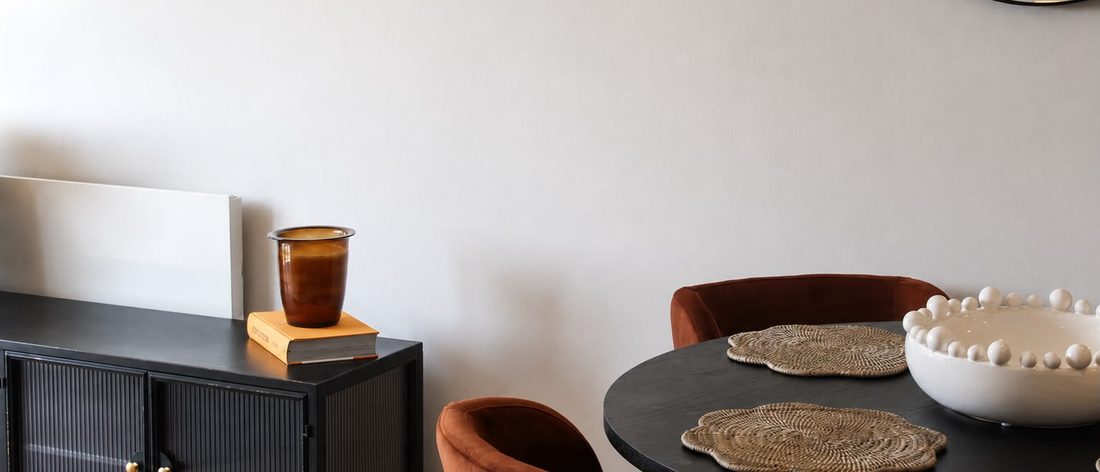 Dining table with velvet chairs beside a fluted black sideboard